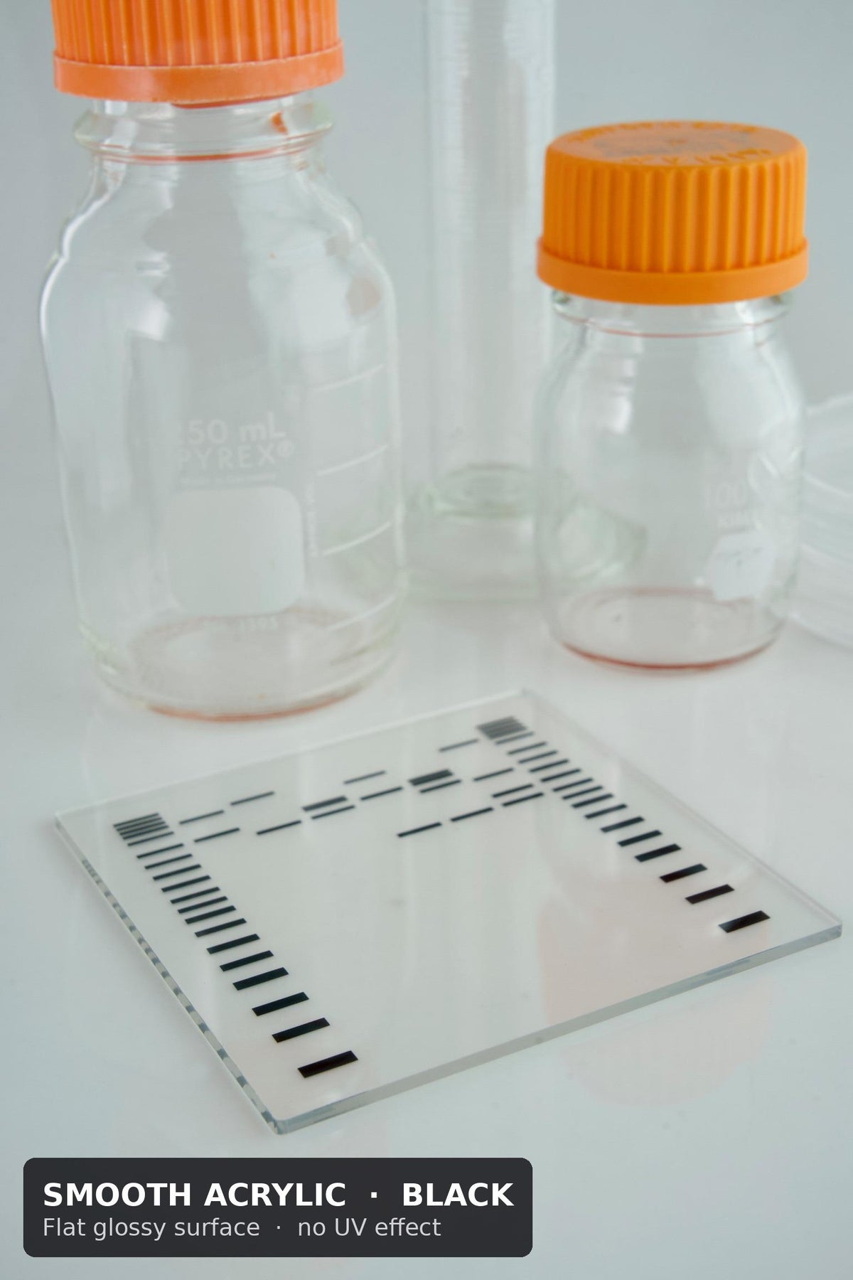 Smooth acrylic DNA gel coaster with black bands and a flat glossy surface, in front of lab bottles